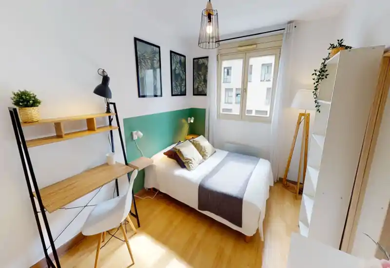 Bright, styled bedroom with a double bed, bedside tables and a study corner. Natural light from the window and tasteful decor make it cozy and welcoming — ideal for rental photos.
