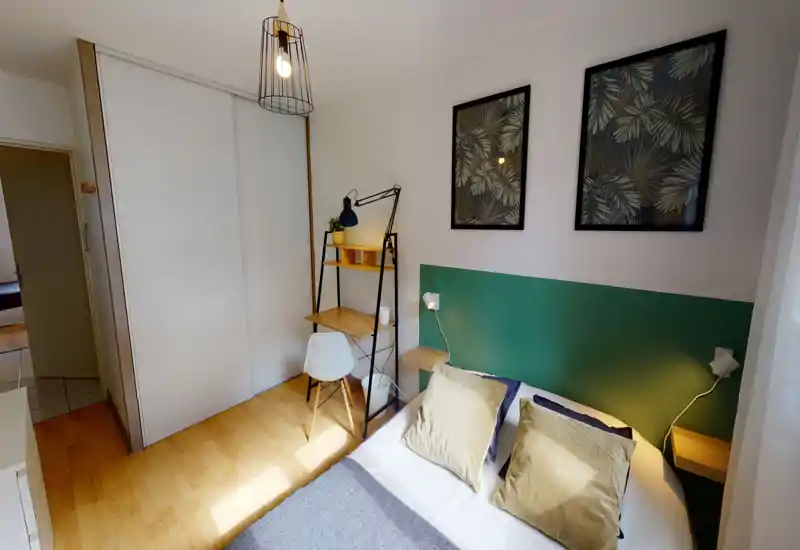 Bright, modern bedroom with a double bed, decorative pillows and bedside lamps; a compact wooden desk and shelving beside a large built-in wardrobe create a functional and stylish layout.