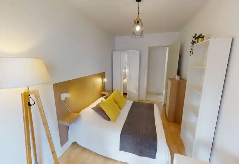Chambre double lumineuse et élégante avec lit en linge blanc, coussins moutarde et couvre-lit foncé. Armoire avec miroir, étagères de chevet, lampadaire et rangements ouverts — idéale pour une annonce de location chaleureuse.