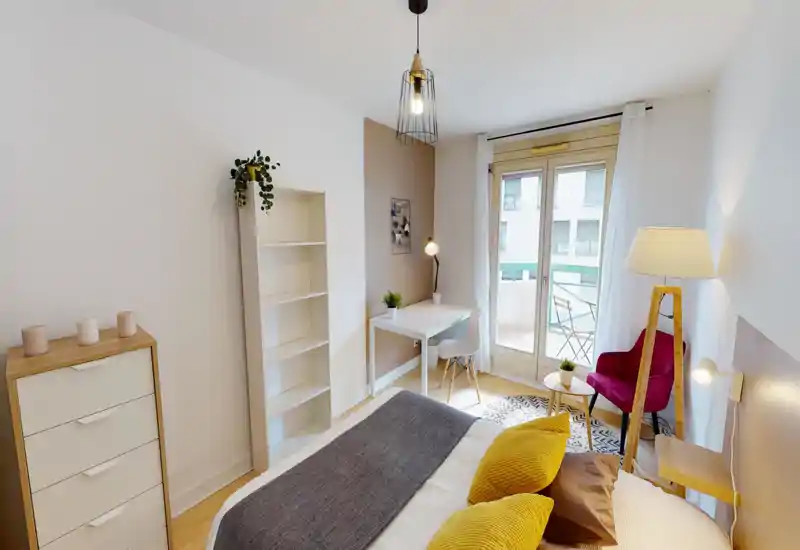 Chambre lumineuse et élégante avec un lit bien fait, des textiles confortables et un petit bureau près de la porte du balcon qui apporte beaucoup de lumière naturelle.