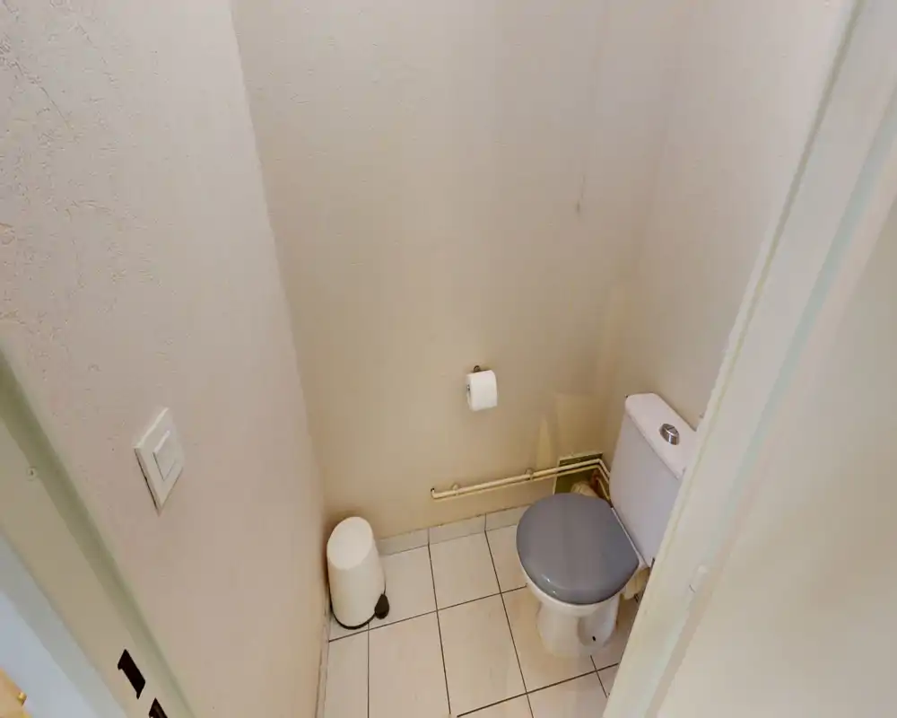 Small, clean separate WC with a closed-coupled toilet, tiled floor and neutral textured walls — practical for a short stay.