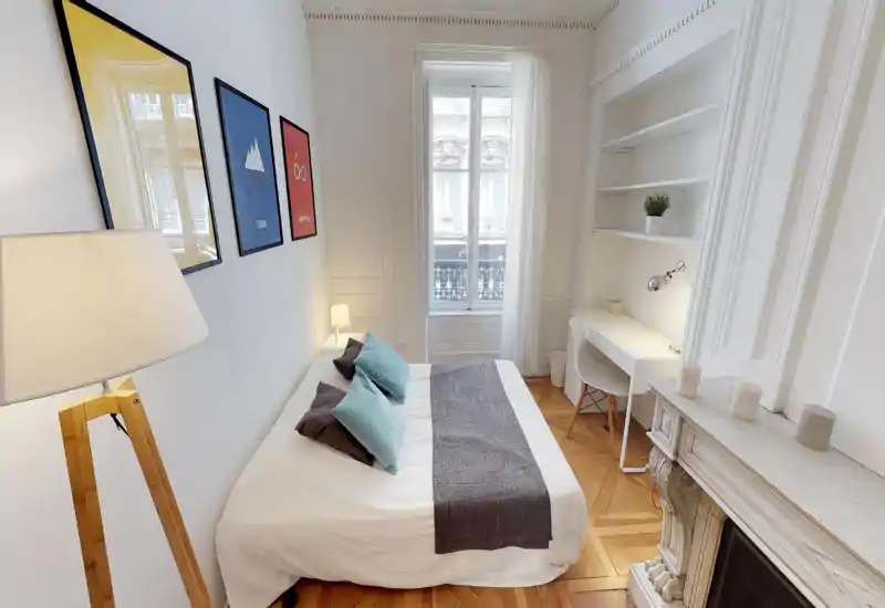 Bright, stylish bedroom with a comfortable double bed, decorative pillows and a desk by the window. Tall window provides natural light; elegant mouldings and parquet flooring add character.
