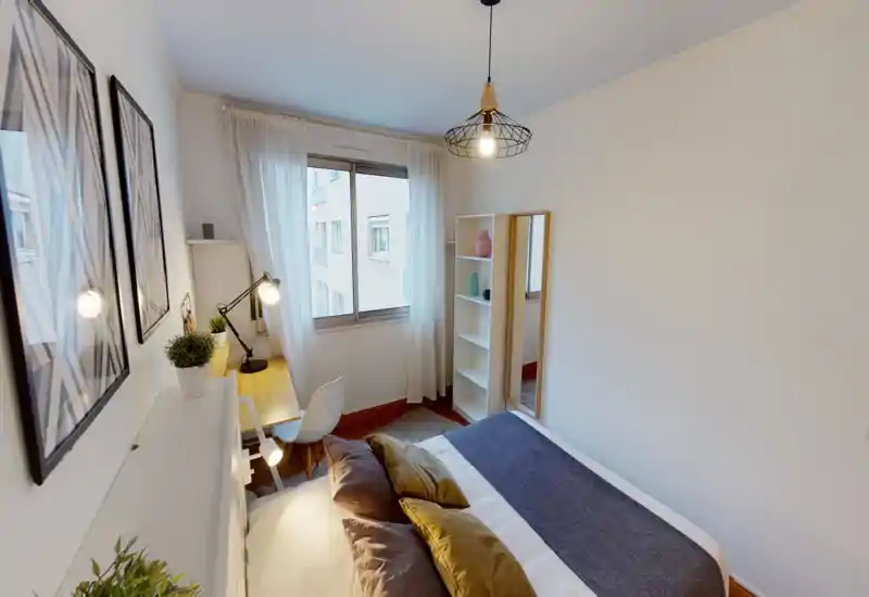 Bright, well-styled bedroom with a double bed, layered pillows and a desk by the window, ideal for a comfortable stay.