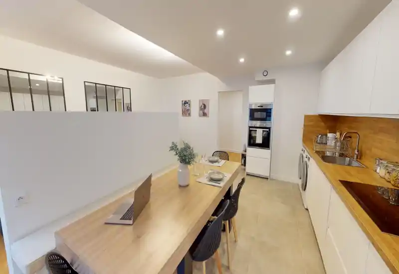 Cuisine moderne ouverte avec grand plan de travail en bois et électroménager intégré, îlot/dînette avec chaises et présentation soignée — lumineuse, fonctionnelle et bien mise en valeur pour une annonce.