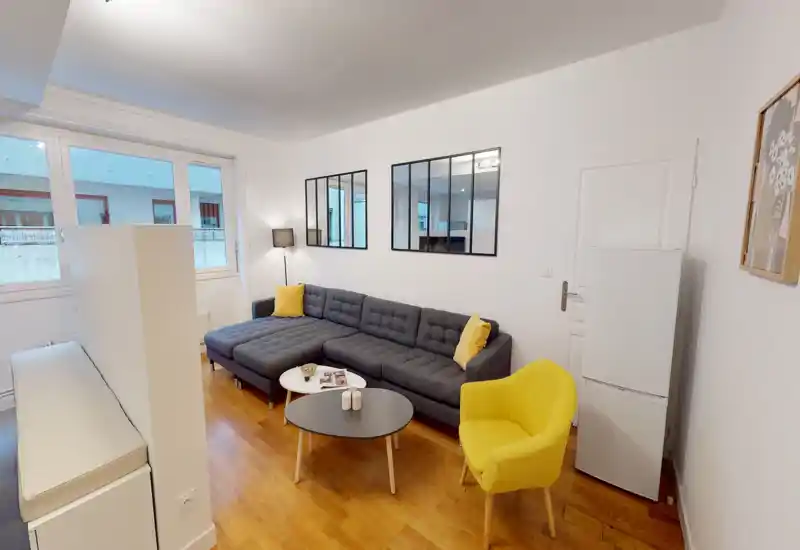 Bright, modern living room with a large grey sectional sofa, yellow accent chair and two nesting coffee tables — ideal for relaxing or entertaining.