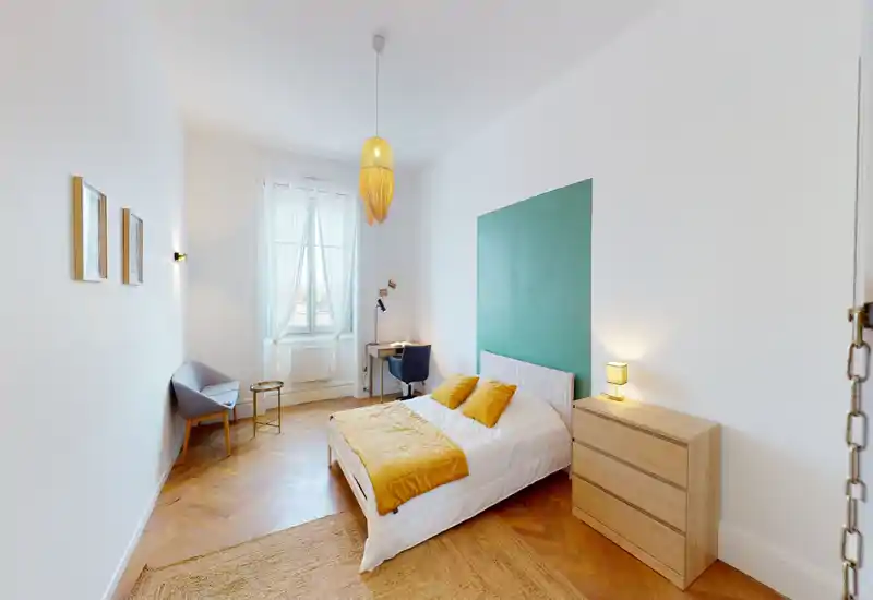 Camera da letto luminosa e di stile con letto matrimoniale, dettagli senape e pannello verde. Comprende comò, una scrivania vicino alla finestra e un tappeto accogliente — ideale per un soggiorno riposante.