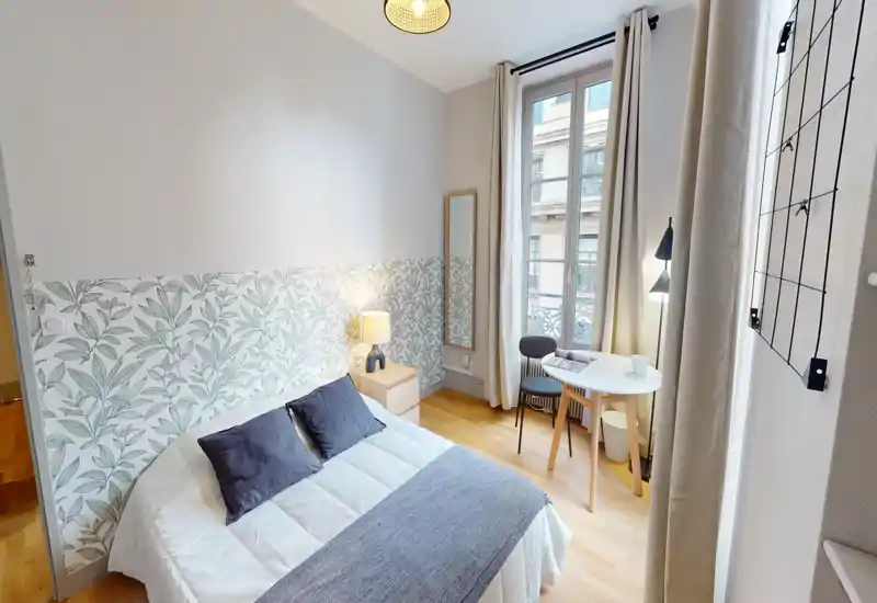 Bright, cozy bedroom with a double bed, bedside table and a small window-side desk — ideal for a comfortable stay or working by natural light.