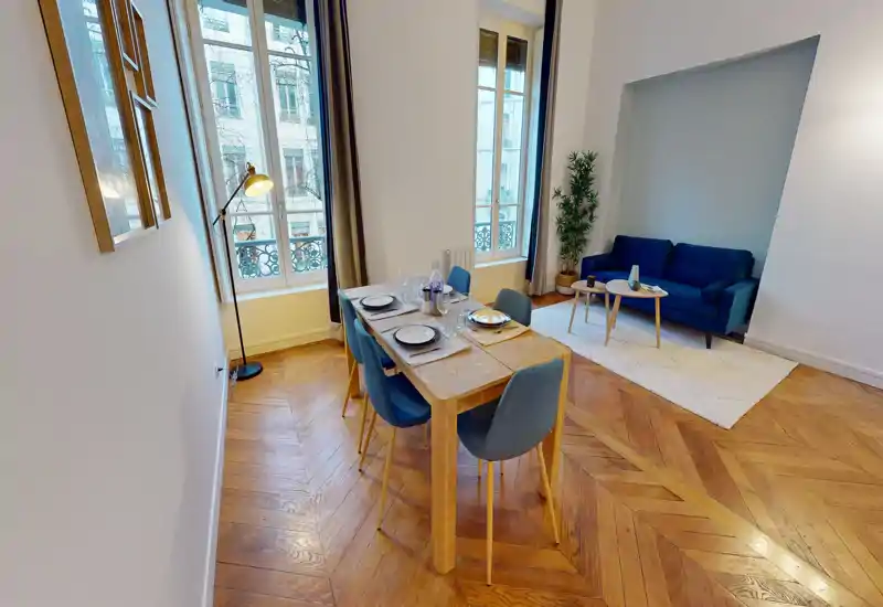 Ampio e luminoso soggiorno con tavolo da pranzo per quattro e un comodo divano in un'alcova — ideale per vivere e mangiare in un appartamento cittadino.