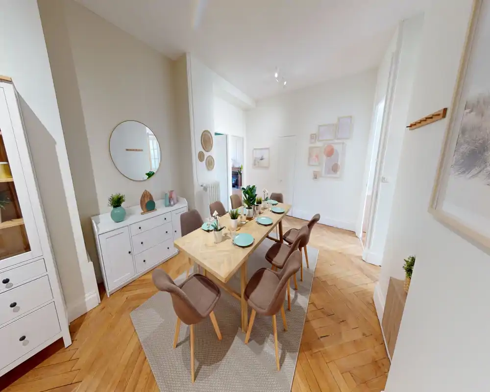 Sala da pranzo luminosa e curata con tavolo in legno per sei persone, sedie imbottite, piatti decorativi e piante che creano un'atmosfera accogliente.
