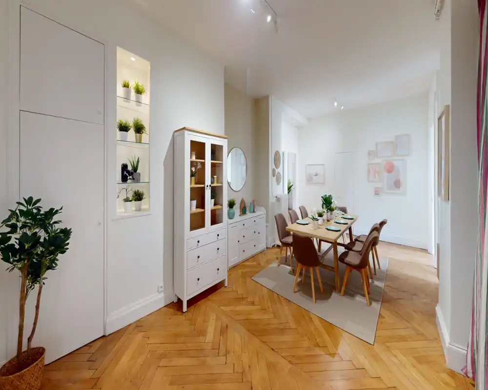 Sala da pranzo luminosa e arredata con tavolo in legno per sei persone, sedie imbottite, credenza decorativa e caldo pavimento in parquet a spina di pesce.