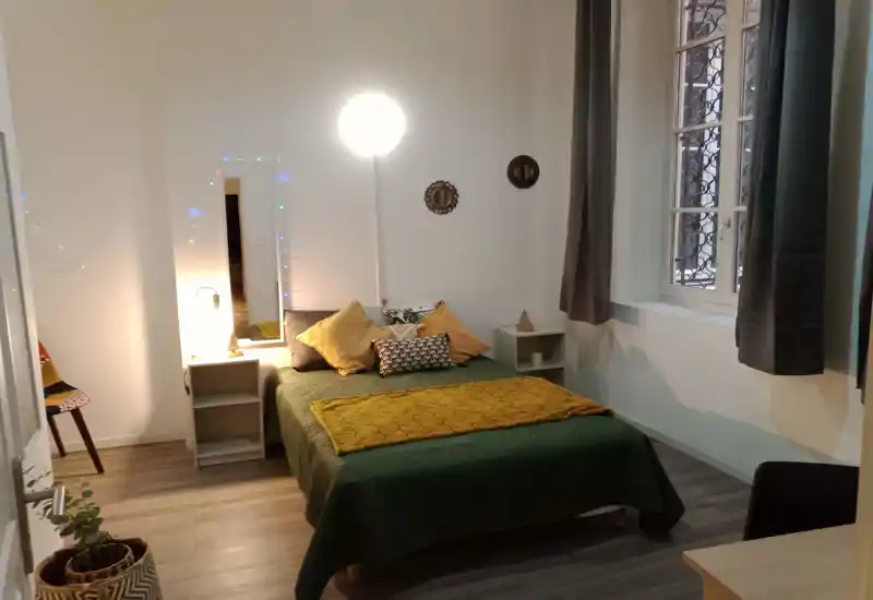 Dormitorio bien presentado con una cama doble cómoda, textiles cálidos y luz suave que crean un ambiente acogedor; ventana amplia para luz natural.