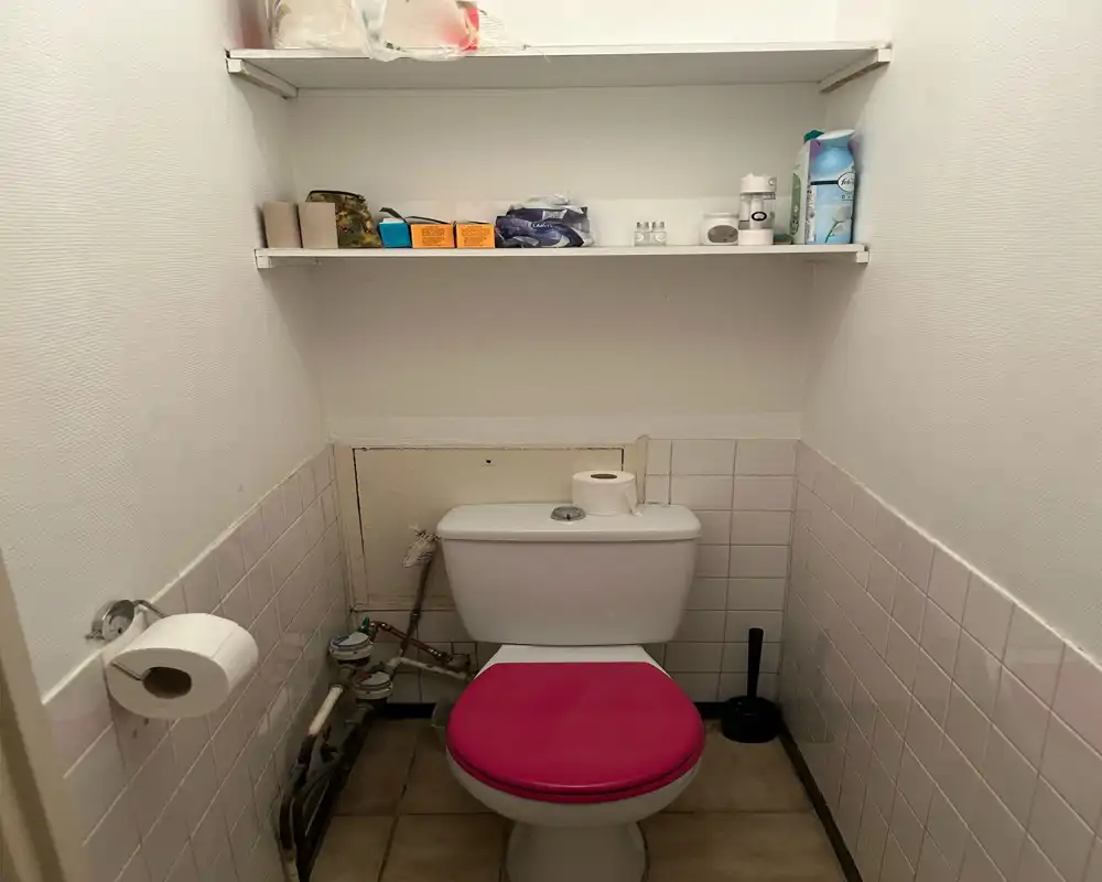Piccolo bagno con wc, mensole a muro sopra lo sciacquone e portarotolo visibile. Lo spazio è compatto e funzionale.