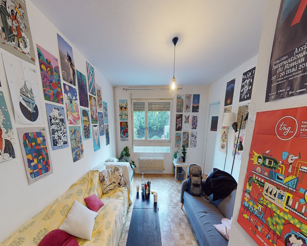 Soggiorno luminoso e ben arredato con due divani di fronte a un tavolino basso, poster colorati alle pareti e luce naturale da una grande finestra — ambiente comune confortevole e di stile.