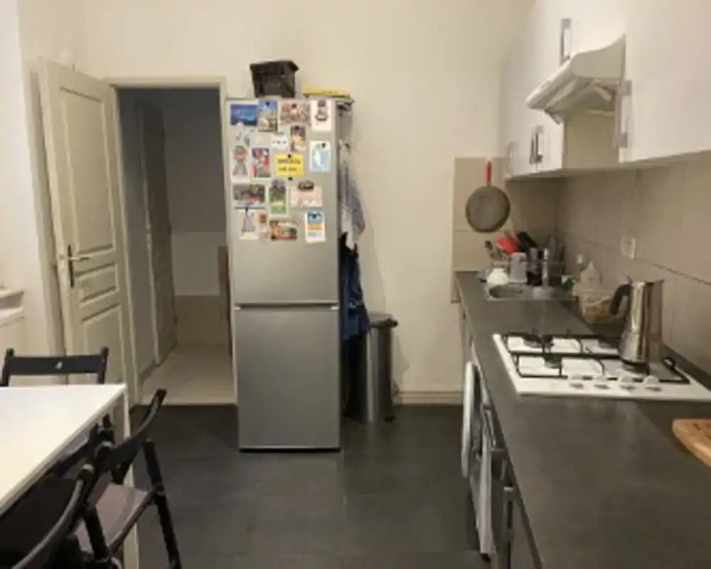 Compact functional kitchen with countertop, stove, sink and a fridge decorated with magnets; practical layout suited for everyday cooking.
