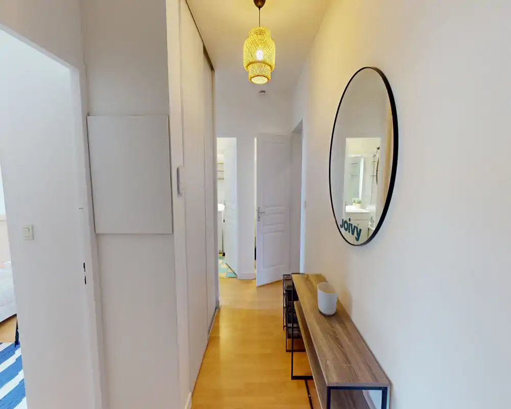 Ingresso/corridoio moderno e luminoso con pavimento in legno, un sottile tavolino console e uno specchio rotondo; conduce alle altre stanze con arredo pulito e accogliente.