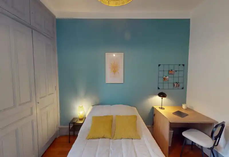 Bright, well-styled bedroom with a centrally placed double bed, warm bedside lamps and a compact work desk — ideal for a comfortable stay.