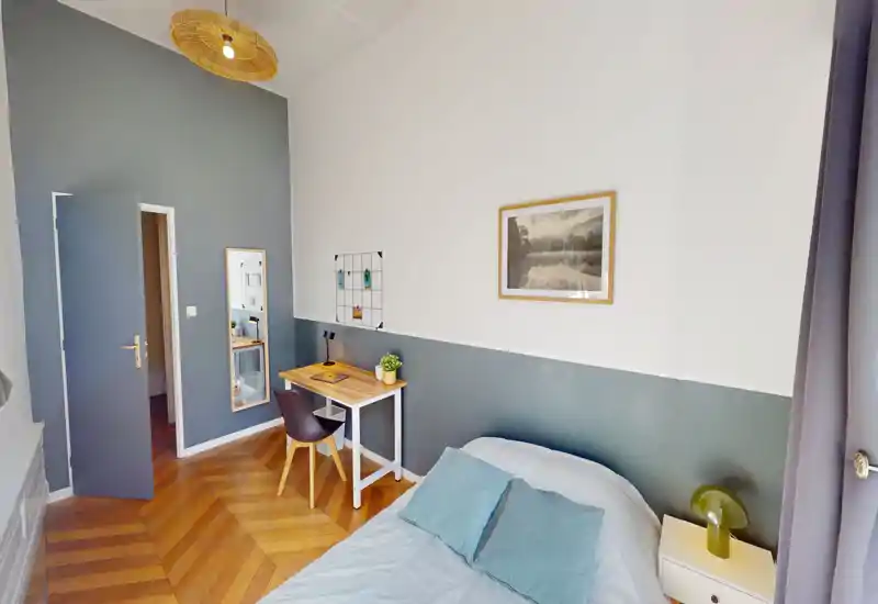 Bright, stylish bedroom with a comfortable double bed, bedside table and a small work desk. High ceilings and wooden herringbone floor add character.