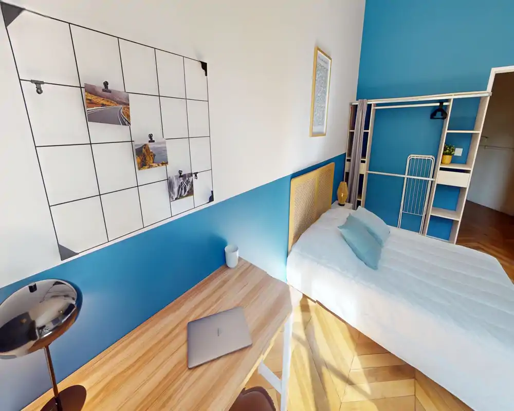 Bright, modern bedroom with a single bed, bedside lamp, open shelving and a small desk—pleasant natural light and coordinated blue accents.