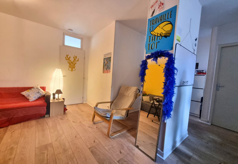 Zona giorno accogliente con divano rosso, poltrona e lampada da terra; pavimento in legno e dettagli decorativi rendono l’ambiente invitante.