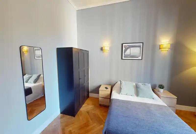 Camera da letto luminosa e di stile con un comodo letto matrimoniale, cuscini morbidi e un'atmosfera calda creata dalle applique a parete e dal pavimento in parquet.
