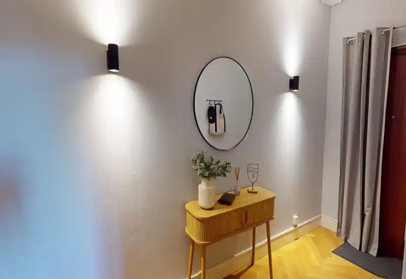 Well-lit entryway with a decorative console table, round wall mirror and soft wall sconces—inviting foyer perfect for welcoming guests.