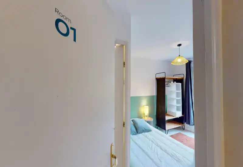 Camera singola luminosa e arredata, con letto rifatto, lampada da comodino e guardaroba a giorno — arredamento moderno e atmosfera accogliente.