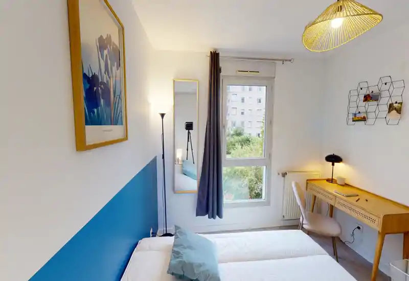 Bright, modern bedroom with a double bed, decorative pillows, a desk and natural light from a window — ideal for short-term rentals.