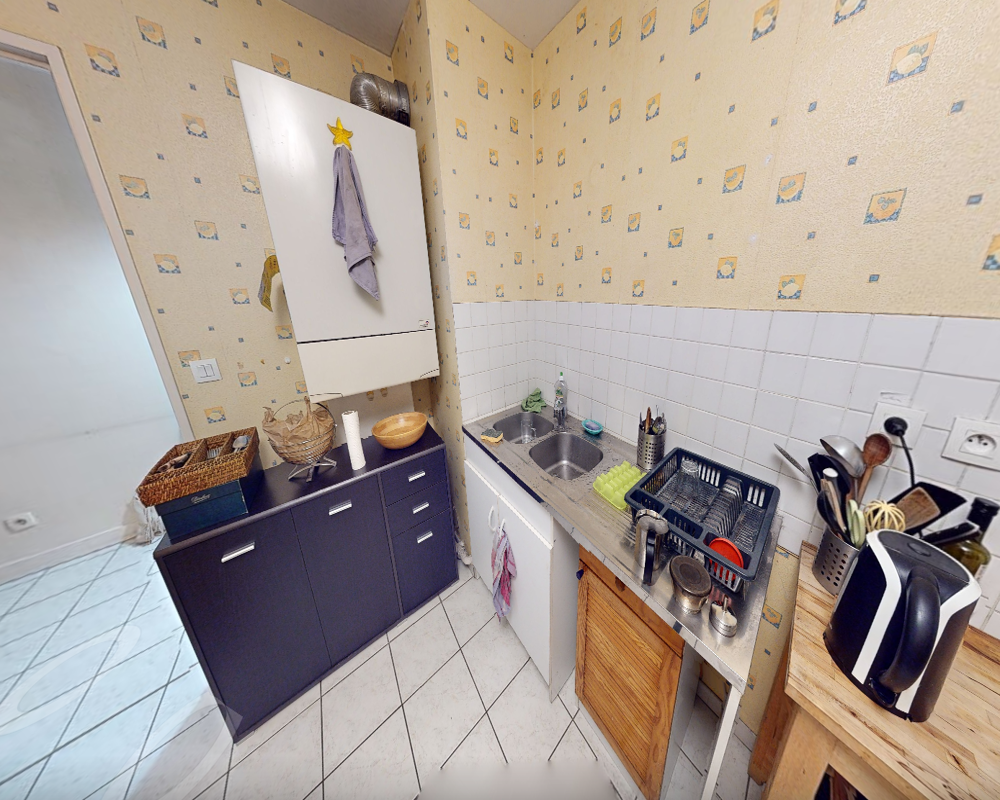 Cuisine compacte et fonctionnelle avec évier double, appareils et rangements — idéale pour la préparation quotidienne et les repas légers.