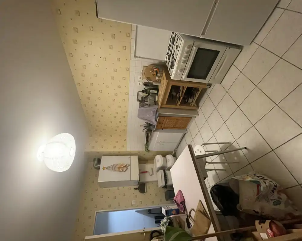 Cuisine fonctionnelle avec cuisinière à gaz, réfrigérateur indépendant, plan de travail et table — espace habité adapté à un petit appartement.