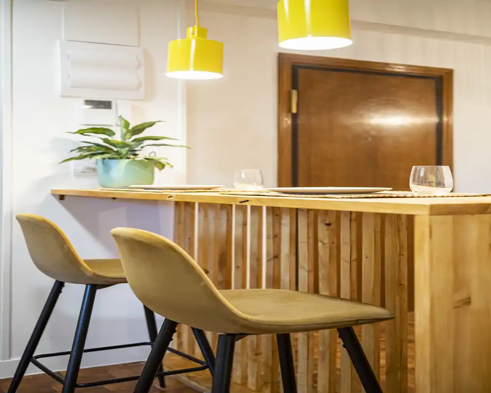 Cozy breakfast bar with two upholstered stools, warm wooden counter and bright pendant lamps — ideal for casual meals and morning coffee.