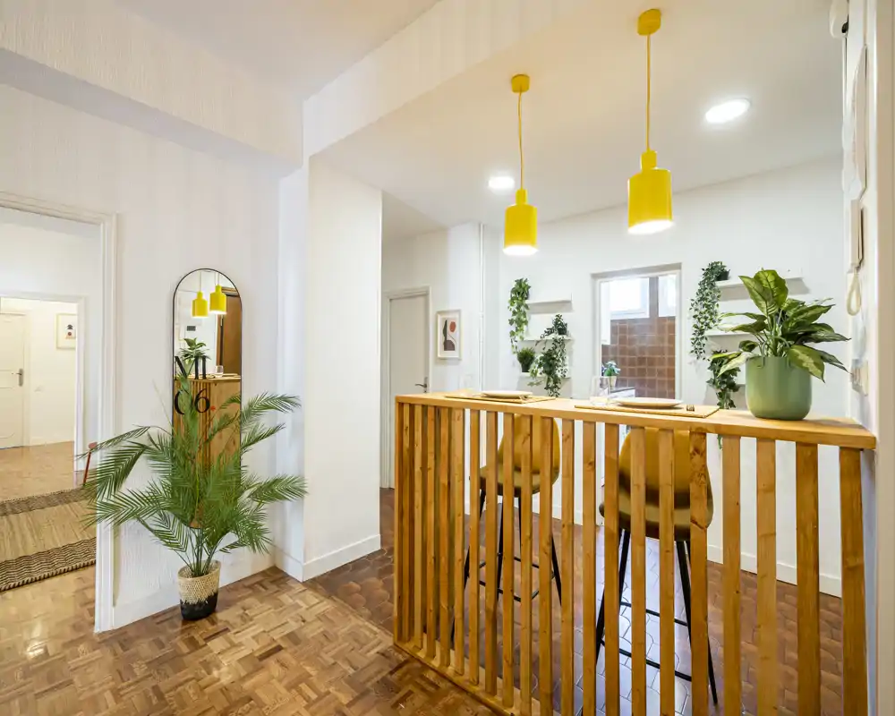 Bright, modern living area with a wooden breakfast bar, pendant lights and indoor plants creating a warm, inviting atmosphere.