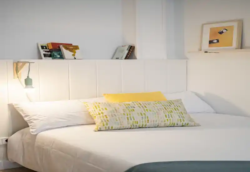 Bright, well-staged bedroom with a large comfortable bed, decorative pillows and soft bedside lighting; ideal for a cozy rental listing.