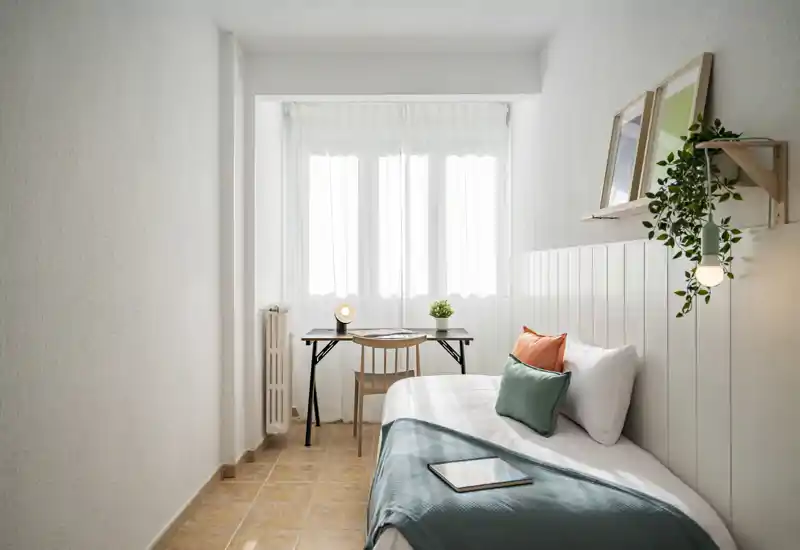 Compact, bright bedroom with a single bed, soft linens and a small desk by the window — ideal for a comfortable stay or work-from-home nights.