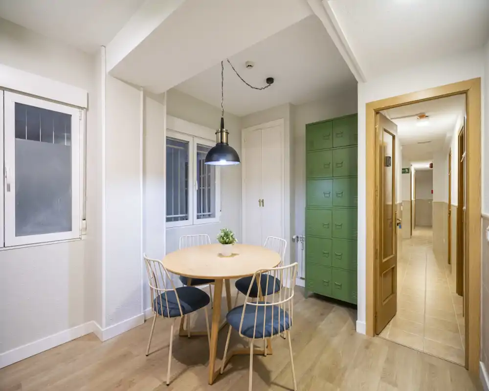 Bright, modern dining nook with a round wooden table, four cushioned chairs and a central pendant lamp — ideal for casual meals.