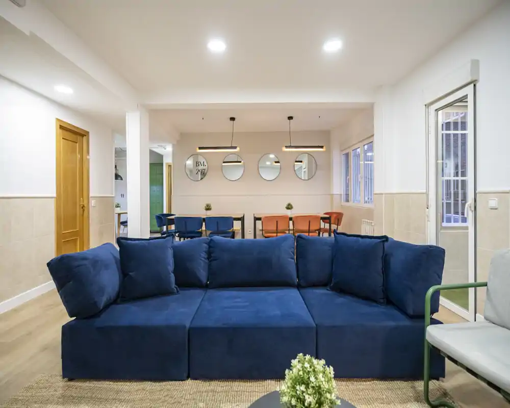 Spacious, modern living room with a deep blue sofa facing an open dining area; bright, well-lit and tastefully styled for comfort.