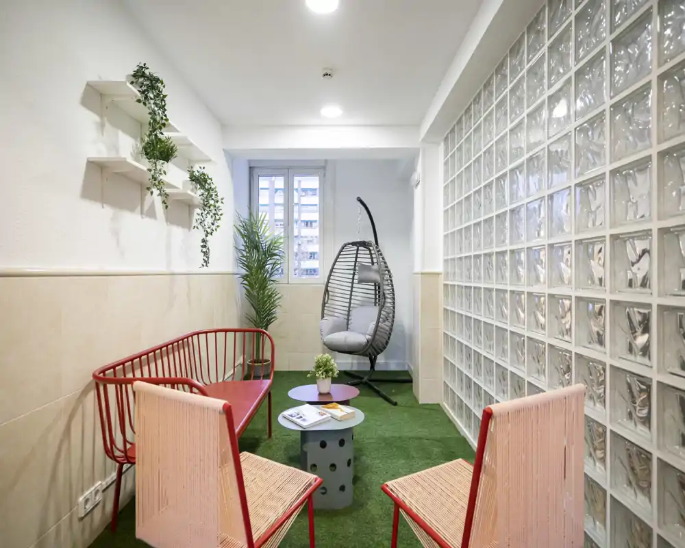 Bright, modern seating area with colorful chairs, a hanging egg chair and decorative plants — a cozy lounge corner ideal for relaxing or casual conversations.