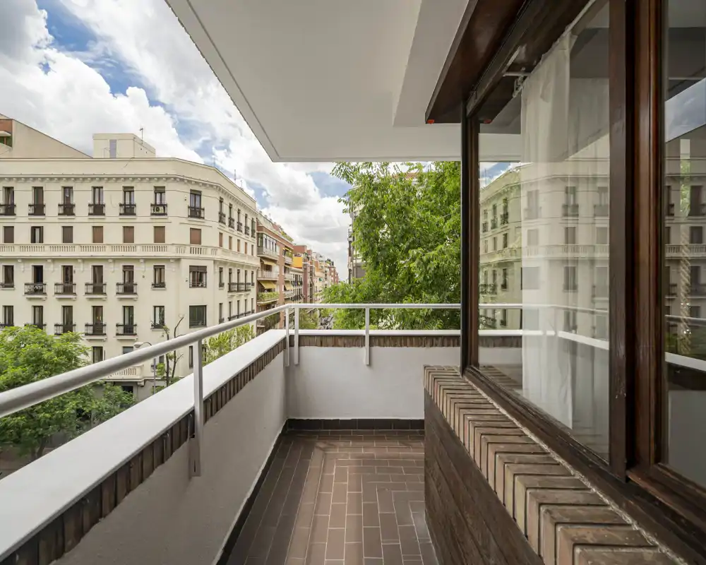 Balcone soleggiato con pavimento piastrellato, ringhiera metallica e piacevole vista sulla città — ideale per un caffè mattutino o per rilassarsi all’aperto.
