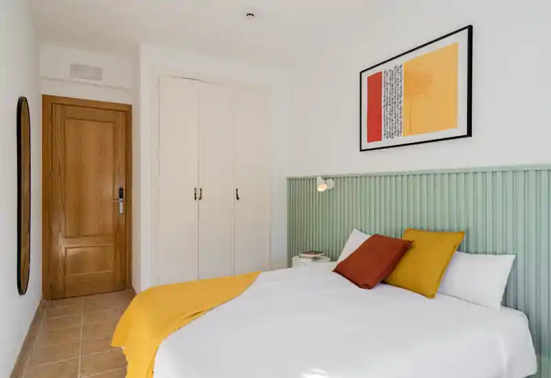 Bright twin-bedroom with two neatly made single beds, headboard running across the wall and warm accent pillows and throws creating a welcoming atmosphere.