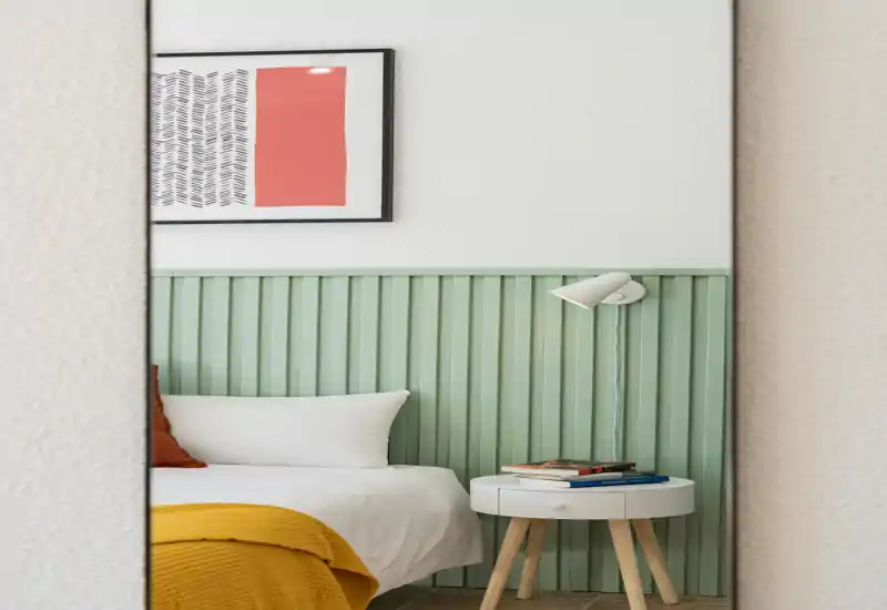 Stylish bedroom photo showing two bedside setups with pillows and layered textiles; image is well lit though heavily distorted by digital artifacts.