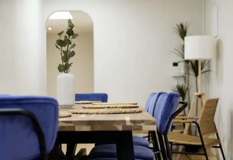 Área de comedor con estilo, mesa de madera maciza, individuales trenzados y sillas tapizadas, iluminación suave para una comida acogedora.