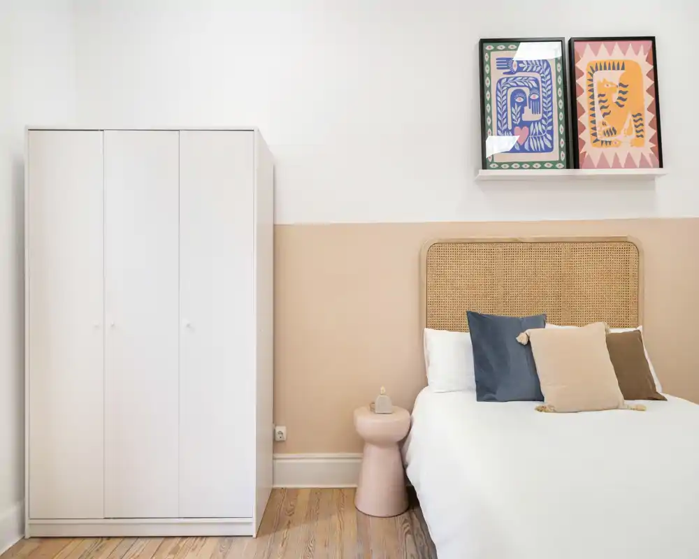 Chambre lumineuse et épurée avec tête de lit en rotin, coussins confortables et armoire blanche — idéale pour une annonce qui met en avant un design minimaliste et soigné.