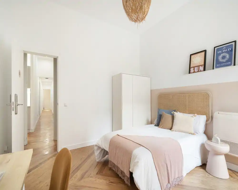 Chambre lumineuse et élégante avec tête de lit tressée, linge de lit doux et parquet chaleureux. L'espace est aéré et bien décoré, parfait pour des photos d'annonce.