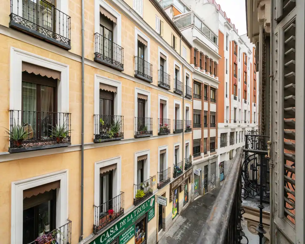 View from a narrow balcony overlooking a charming city street with classic building façades and small decorative railings.