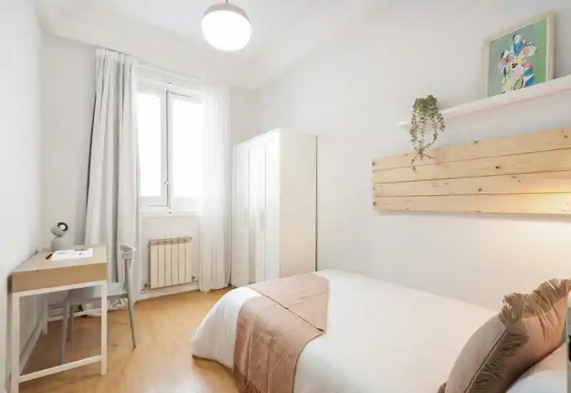 Bright, well-styled single bedroom with a neatly made bed, wardrobe, small desk and soft natural light from the window — ideal for a rental listing highlighting a cozy, minimalist space.
