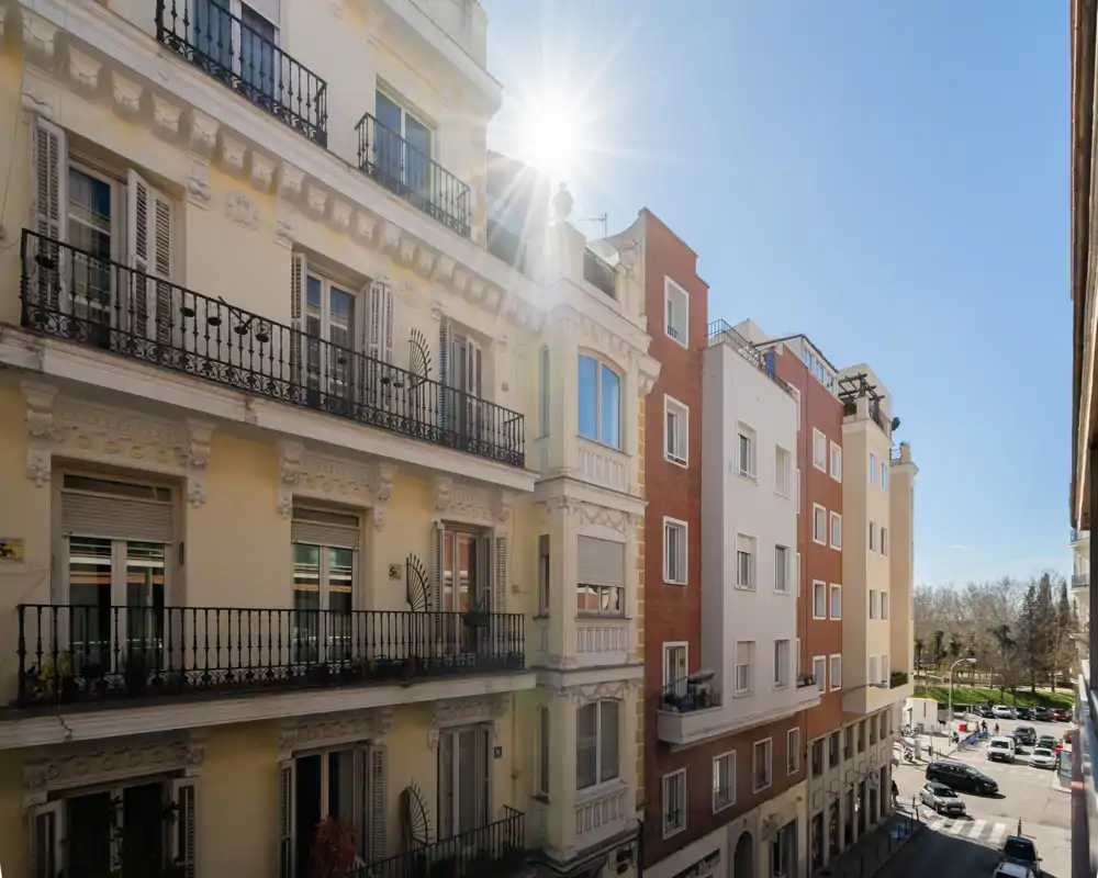 Vista soleada de la calle y las fachadas de los edificios con cielo despejado, ideal para mostrar los alrededores y la iluminación del vecindario.