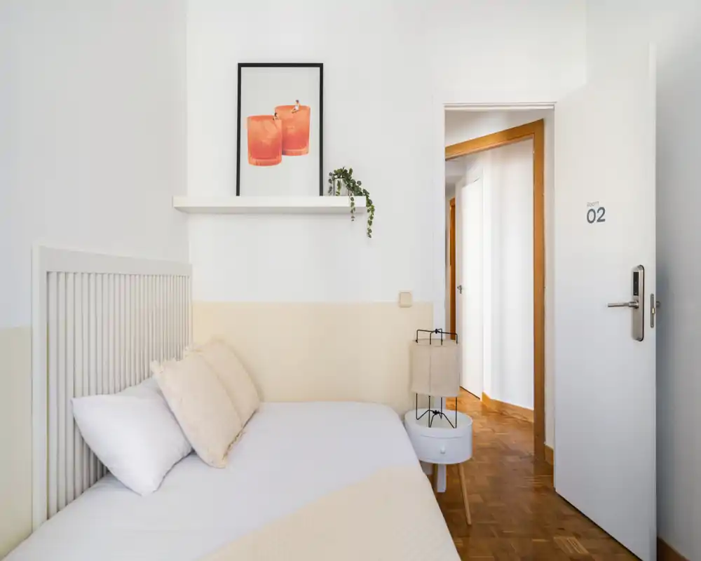 Chambre lumineuse et minimaliste avec lit bien fait, textiles chaleureux et décoration sobre — parfaite pour un repos calme.