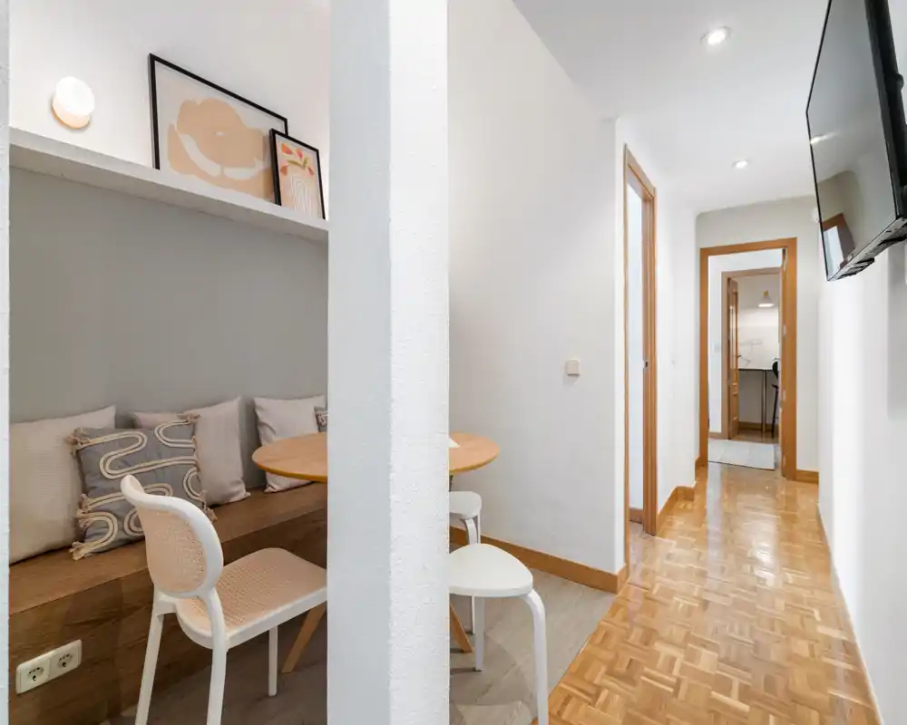 Bright, well-kept entrance hallway with parquet flooring, wall-mounted TV and a cozy built-in bench dining nook visible to the side.