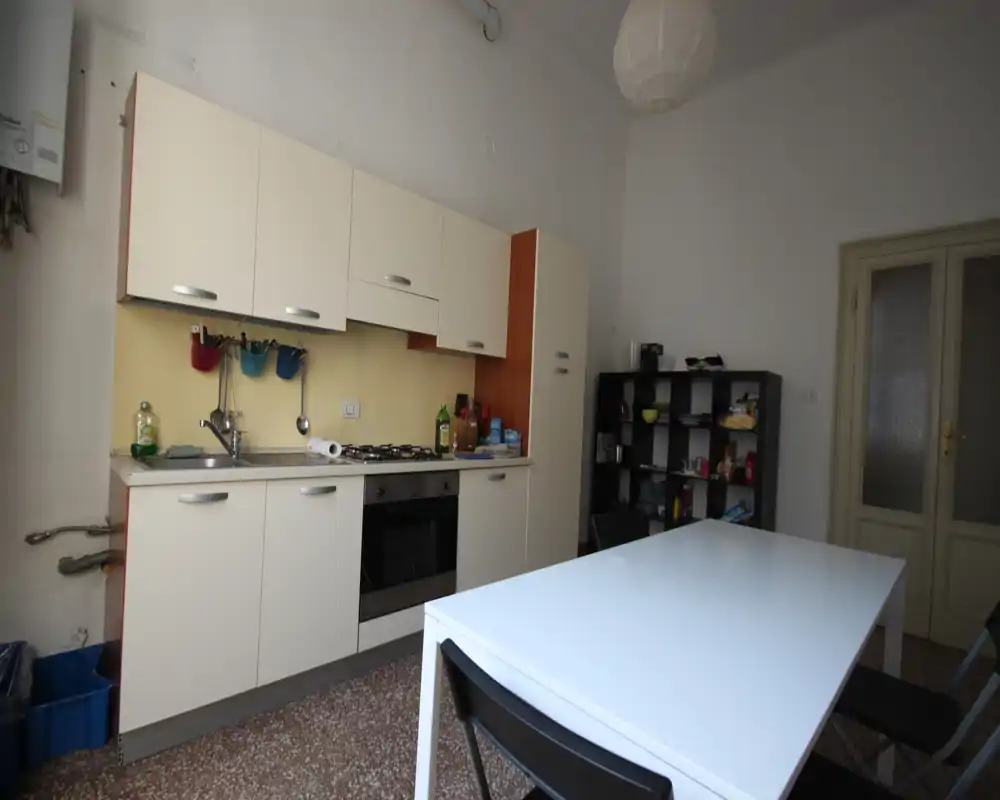 Cocina compacta y funcional con armarios empotrados, placa de gas y horno, y una mesa de comedor — luminosa y práctica para el uso diario.