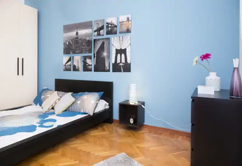 Camera da letto moderna e luminosa con letto basso, cuscini decorativi e quadri coordinati che creano un'atmosfera elegante e rilassante.