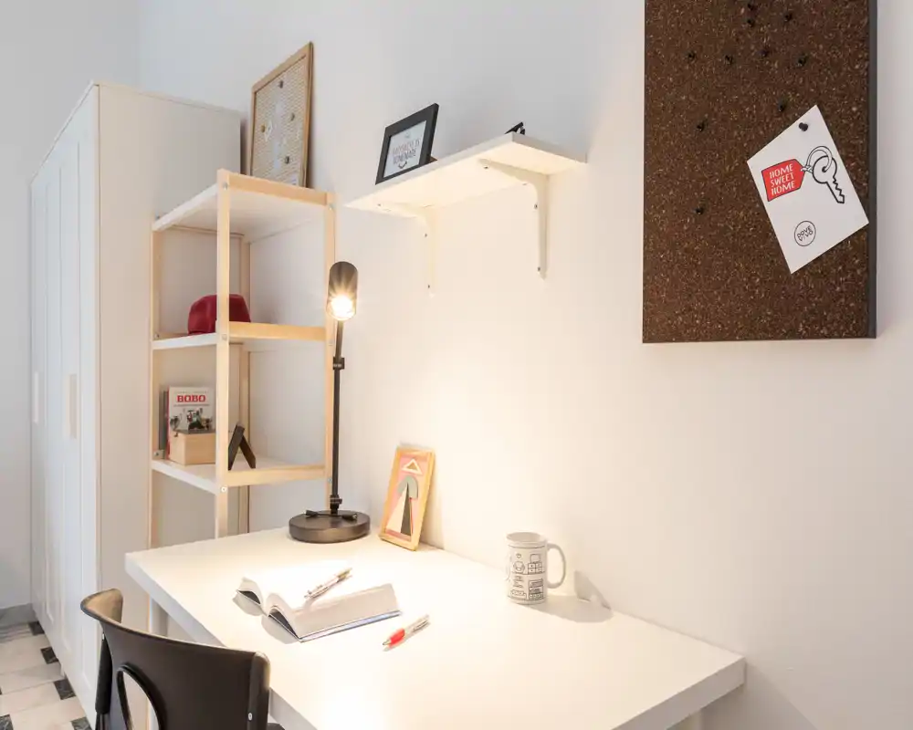 Bright, minimalist study corner with a white desk, task lamp and shelving — ideal for work or reading. Clean lines and neutral tones create a calm, functional workspace.